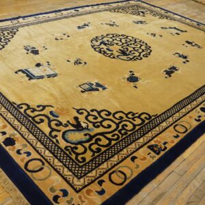 A large golden-yellow rug with deep blue Chinese patterns and borders lies on rustic wooden flooring.