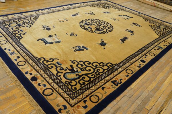 A large golden-yellow rug with deep blue chinese patterns and borders lies on rustic wooden flooring.