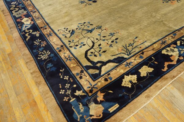 Olive beige rug with navy and tan border displaying trees, blue birds, and florals on wood floor.