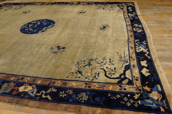 Large tan rug featuring a dark blue medallion, elaborate borders, and floral patterns on wood floors.