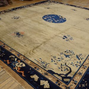 Square beige rug featuring a central blue bird medallion and scattered blue and orange floral motifs on wood floor.