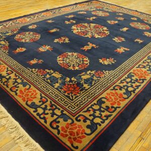 Navy blue rug featuring intricate gold and red medallions and borders on golden wood flooring.