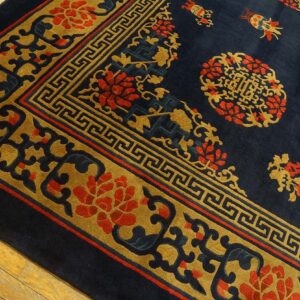 Thick pile navy blue rug featuring gold and red ornate floral and geometric patterns over wood floor.