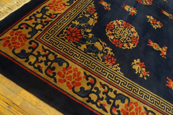 Thick pile navy blue rug featuring gold and red ornate floral and geometric patterns over wood floor.