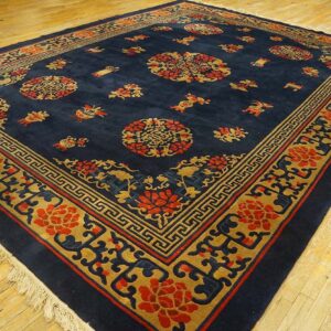Plush navy rug displaying an intricate red and gold medallion and geometric border design on wood planks.