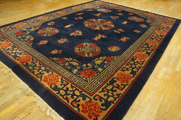 Plush navy rug displaying an intricate red and gold medallion and geometric border design on wood planks.