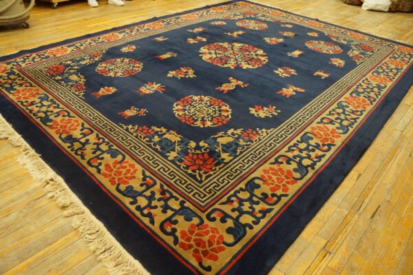 Deep blue rug with scattered red and tan floral medallions and geometric borders on hardwood flooring.