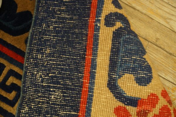 Detail of a rolled rug showing the navy, red, and tan geometric pattern and textured woven back.