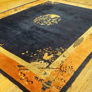 Large dark blue rug with gold and orange floral borders on reflective golden hardwood flooring.