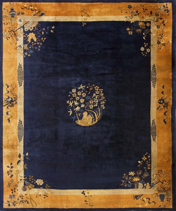 A deep blue rug with a wide gold botanical border and a centered golden floral figure design.
