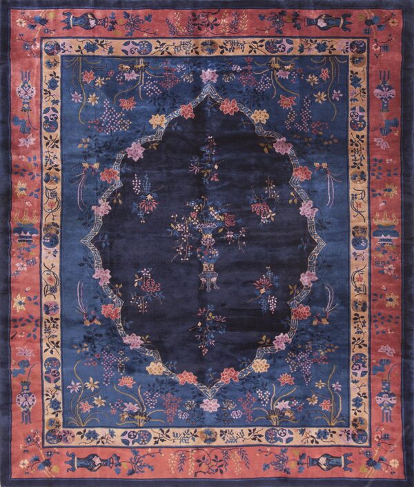 Dark blue floral rug featuring a central lobed design and a wide rose-colored border with vases.
