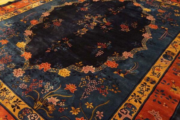 A plush blue rug with a central floral medallion outline and orange, pink, and yellow botanical motifs.
