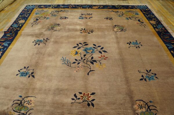 Low-pile tan rug with colorful floral sprays and a navy border, displayed on hardwood flooring.