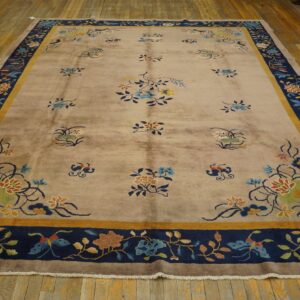 Beige rug with multicolored scattered florals and a wide navy and gold patterned border on wood floor.