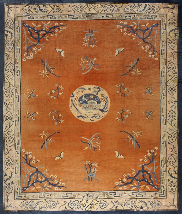 High-pile orange rug with blue and cream accents, featuring a central medallion and botanical motifs.