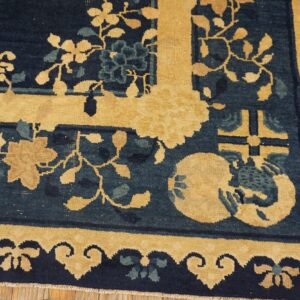 A close-up view shows a low-pile rug with navy blue, goldenrod, and teal floral patterns over wood flooring.