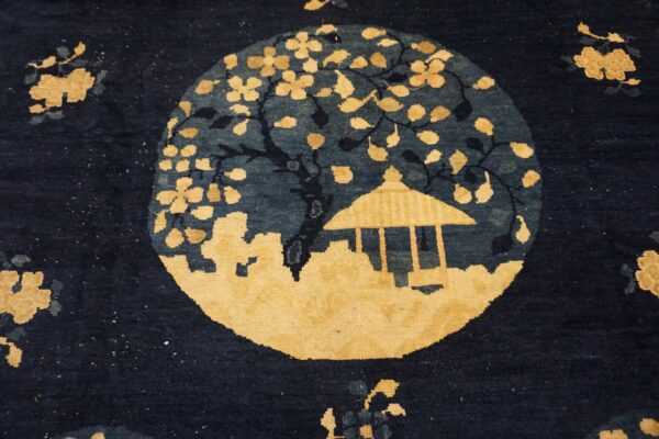 Medium pile rug detail featuring a yellow scenic medallion with a tree and pavilion on a navy blue field.