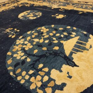 Textured navy and gold rug with stylized circular medallions displayed on wooden plank flooring.