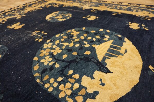 Textured navy and gold rug with stylized circular medallions displayed on wooden plank flooring.