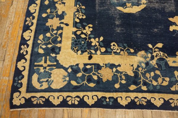 Close-up of a distressed navy and gold rug featuring a detailed floral border on rustic wood flooring.