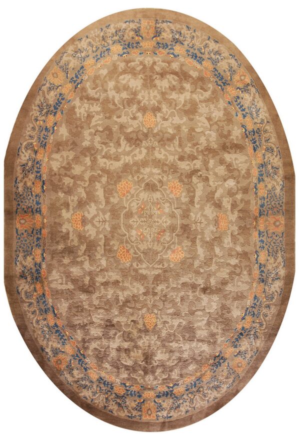Oval tan rug with tone-on-tone scrolling patterns and a bright blue and orange floral border.