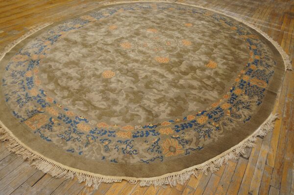 Round olive and tan rug with bright blue and apricot floral borders on distressed wood floors.
