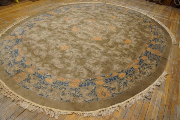 Circular olive rug with tone-on-tone cloud pattern, blue and peach floral border, and prominent white fringes.