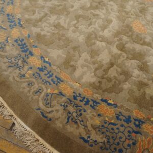 High-pile round rug in neutral taupe with blue and peach floral borders rests on rustic wood flooring.