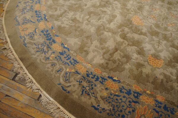 High-pile round rug in neutral taupe with blue and peach floral borders rests on rustic wood flooring.