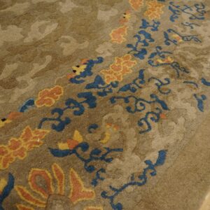 High-pile beige rug with subtle background pattern and vibrant blue, coral, and yellow floral accents.
