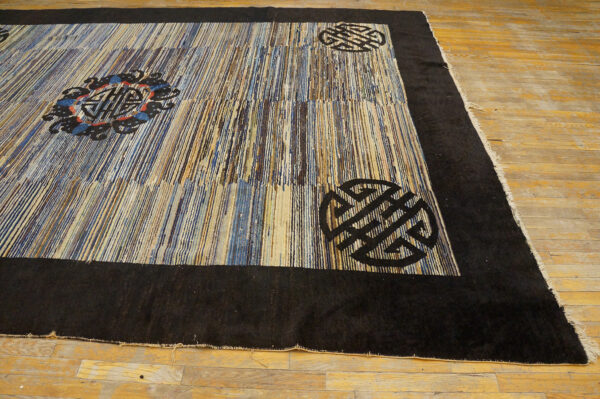 Textured rug featuring vertical blue, brown, and beige stripes with a black border and stylized corner motifs.