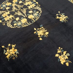 Dark blue rug with scattered yellow floral clusters, a large medallion, and a striped cream border.
