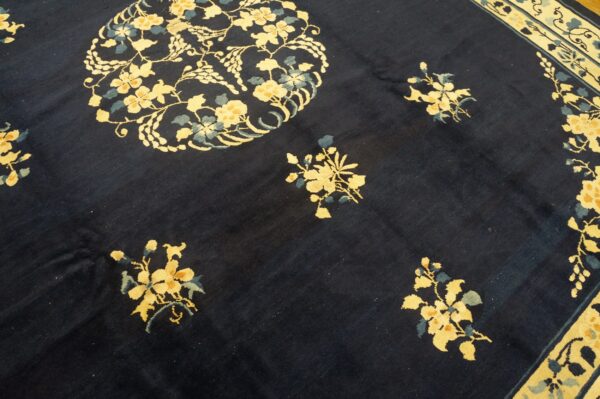 Dark blue rug with scattered yellow floral clusters, a large medallion, and a striped cream border.
