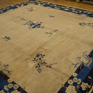 Beige rug with scattered blue motifs and a wide navy border, shown on a wood plank floor.