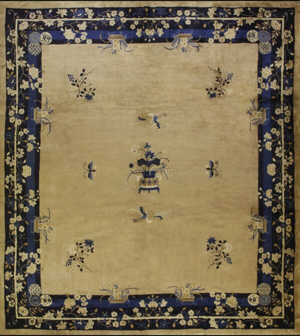 Square beige rug with a detailed navy blue floral border and a central design of a vase and birds.
