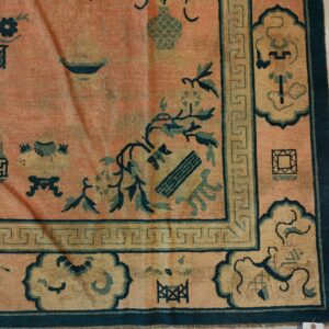 Salmon rug with teal Oriental motifs, a yellow cartouche border, and a Greek key design.