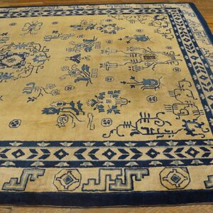 Golden yellow rug with scattered indigo patterns and elaborate blue borders on warm hardwood flooring.