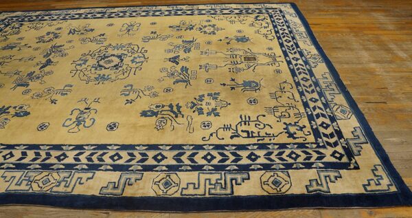 Golden yellow rug with scattered indigo patterns and elaborate blue borders on warm hardwood flooring.