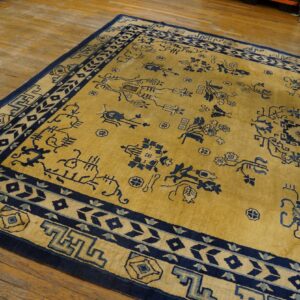 Gold and navy patterned rug on a hardwood floor, showing scattered stylized motifs and wide borders.