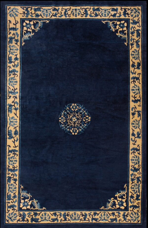 High-pile navy blue rug with a beige floral border and a small matching blue and tan center medallion.