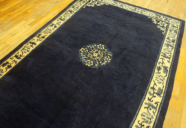 Rectangular dark blue rug with yellow and blue decorative borders on polished wood planks.