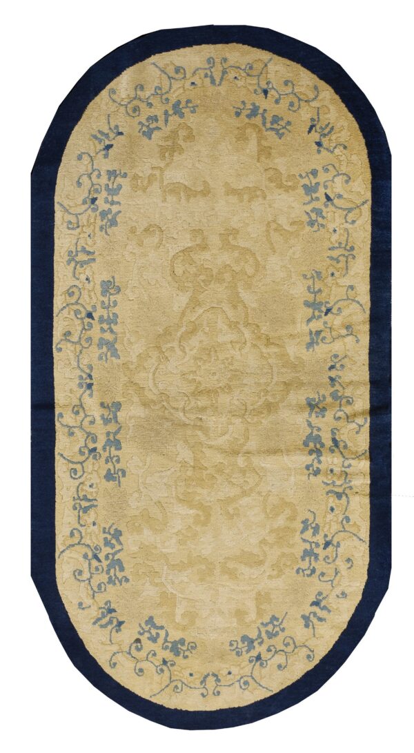 Oval gold and navy rug with subtle carved texture and light blue floral vine designs.