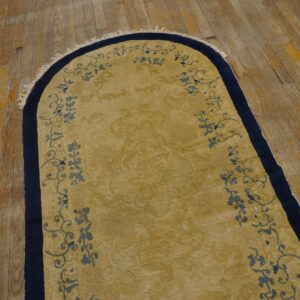 Arched golden rug with scrolling blue motifs and a navy border on worn wood flooring.