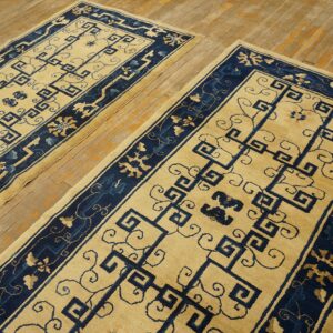 Pair of yellow and navy runner rugs featuring geometric fretwork patterns on a wood floor.