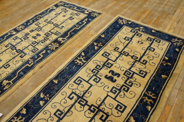 Pair of yellow and navy runner rugs featuring geometric fretwork patterns on a wood floor.