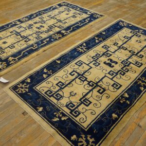 A pair of cream and indigo runners with geometric patterns rests on a distressed wooden floor.