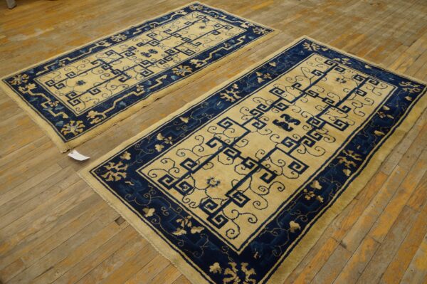 A pair of cream and indigo runners with geometric patterns rests on a distressed wooden floor.