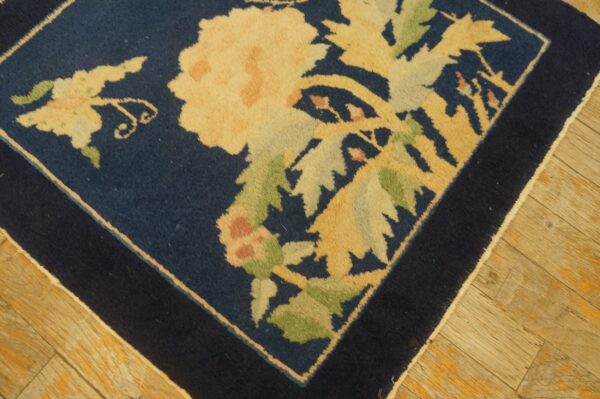 Antique peking square small scatter size wool black & navy rug 6 Dark blue square rug with large pale yellow and green floral motifs rests on distressed light wooden flooring.