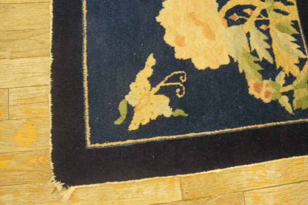 Antique peking square small scatter size wool black & navy rug 7 Thick pile, navy blue square rug displaying large yellow and green floral designs sits on light golden wood planks.