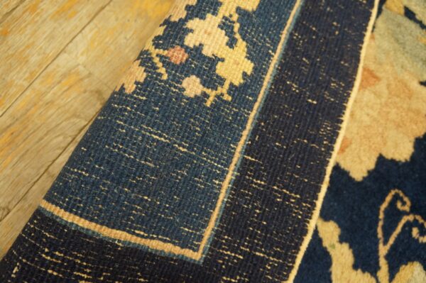 Antique peking square small scatter size wool black & navy rug 8 Deep blue and light tan patterned square rug detail, showing the border curled on wood floorboards.